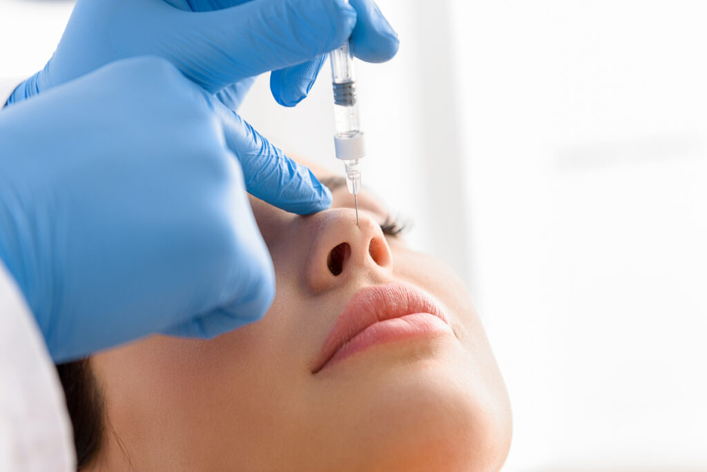 Doctor hand injecting in face of calm woman
