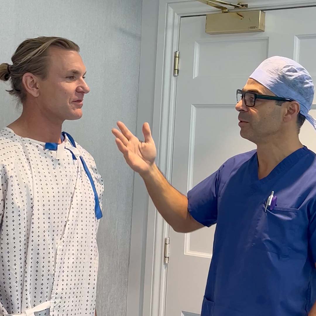 A man in surgical scrubs is speaking to a patient