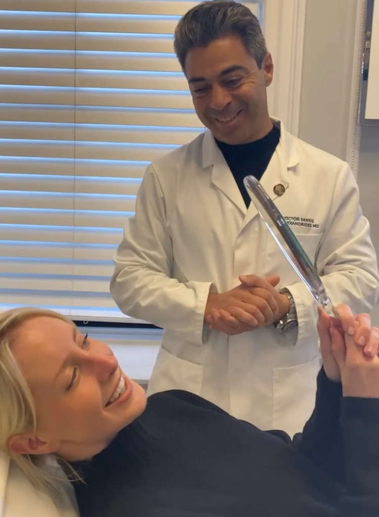 A doctor smiles at a patient who is looking in the mirror happily