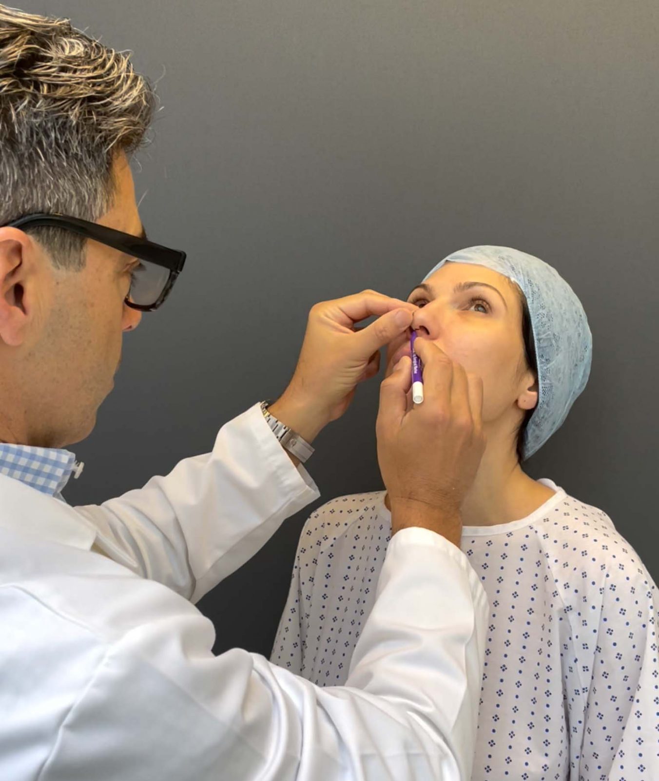 A woman is getting her nose marked for surgery.