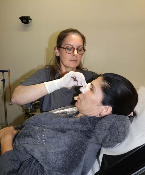 A woman is having her nose cast removed after surgery