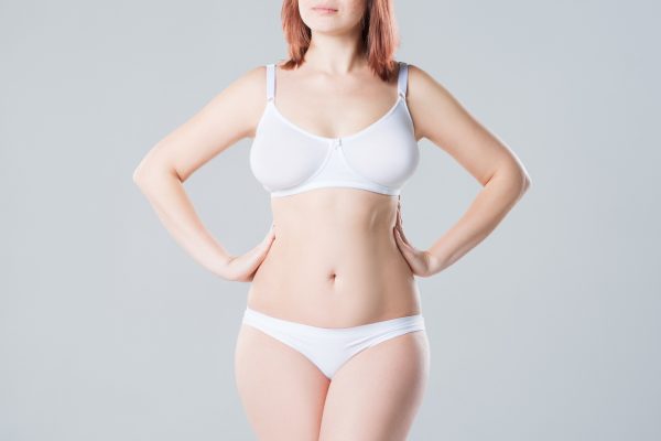Young slim woman in underwear on grey background, beautiful female body