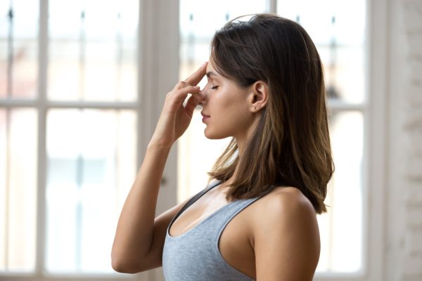 Young woman practicing yoga, nadi shodhana pranayama pose, close up