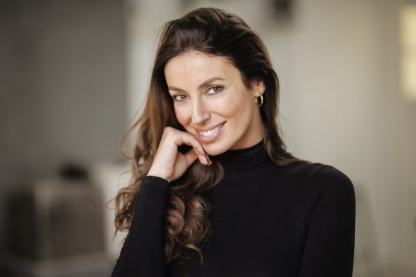 Close-up portrait of an attractive brunette haired woman looking at camera and cheerful smiling.