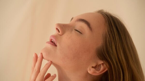 Woman with closed eyes touching her chin gently